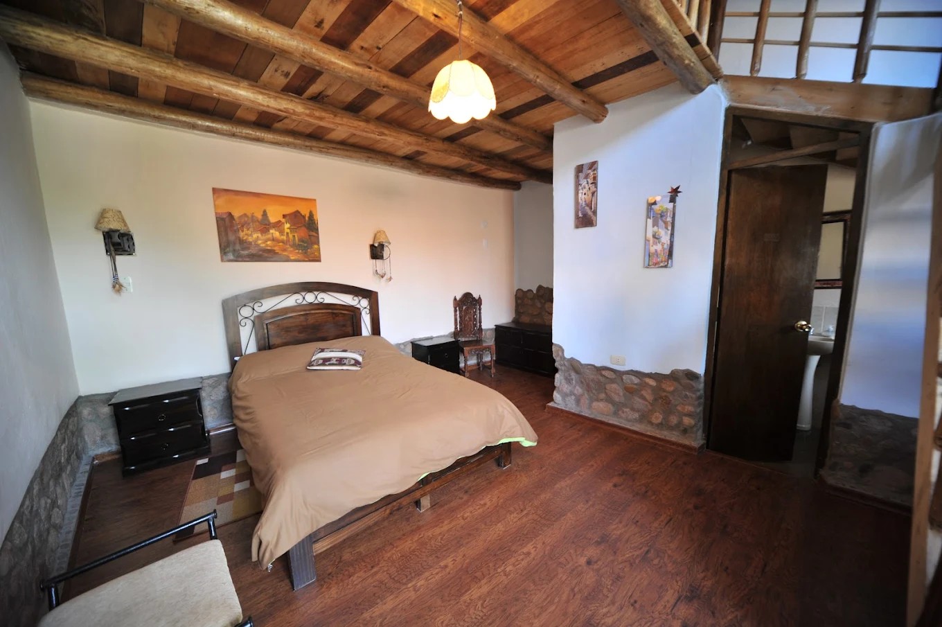 A bedroom with a double bed, a wooden floor and a beamed ceiling