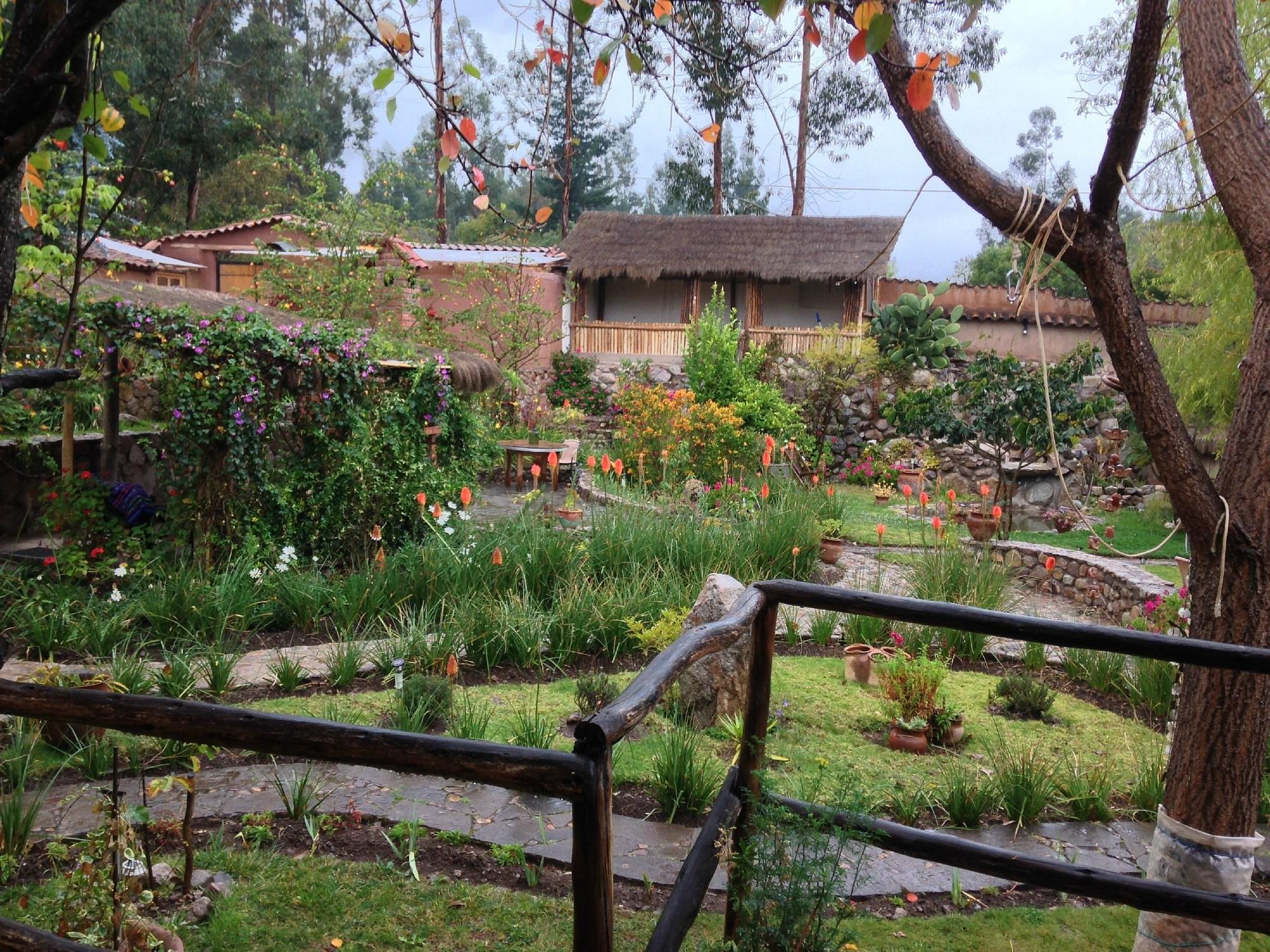 The garden at La Capilla Lodge, flower beds and stone paths behind a wooden rail