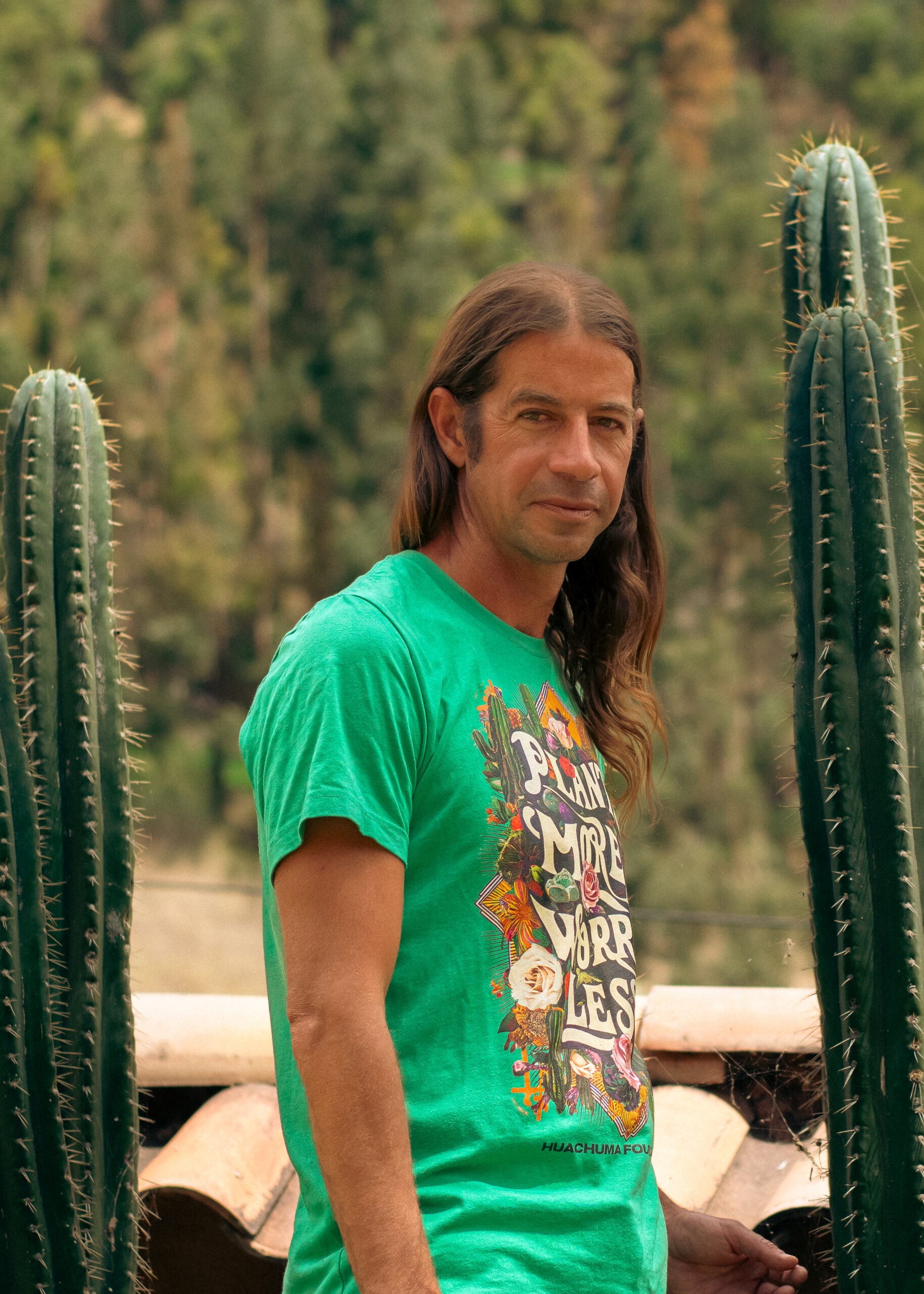 Miguel Mendiburu in a green T-shirt, standing between two tall cacti